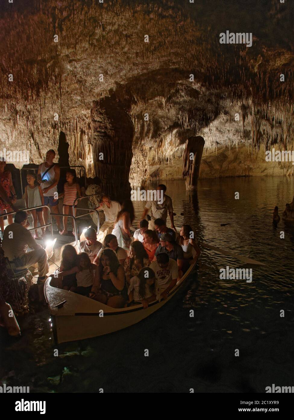 Touristes se rendant sur un voyage en bateau dans une grotte de calcaire inondée avec de nombreuses stalactites et stalagmites, grottes de Drach / Cuevas del Drach, Porto Banque D'Images