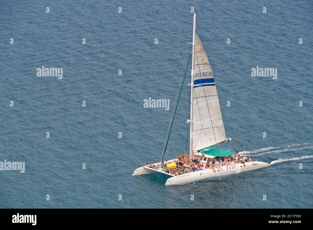 Catamaran plein de jeunes lors d'une excursion en bateau de fête le long de la côte de la péninsule de Llevant, près de Port d'Alcudia, côte nord-est de Majorque, août. Banque D'Images