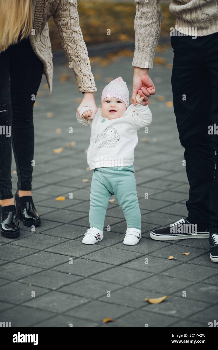 Les parents holding satisfait par les mains de l'enfant pendant qu'il marche. Banque D'Images