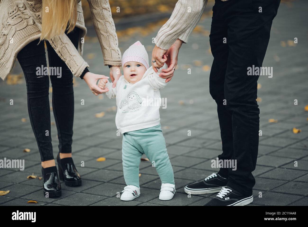 Les parents holding satisfait par les mains de l'enfant pendant qu'il marche. Banque D'Images
