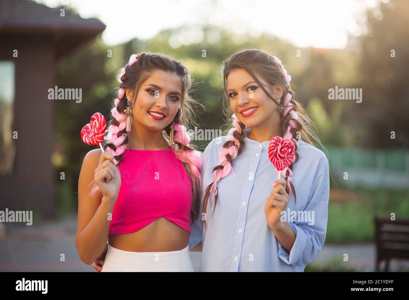Les filles à la mode avec des tresses de bonbons coeur sur stick. Banque D'Images