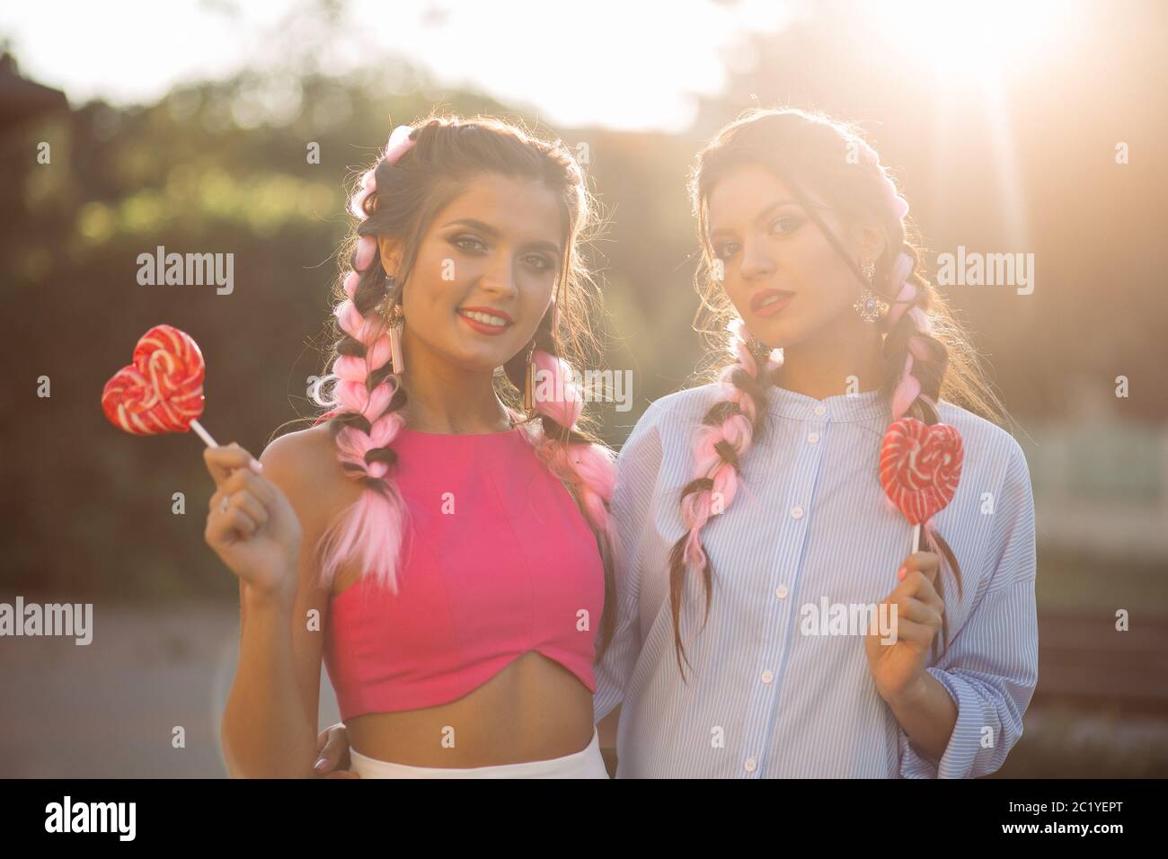 Les filles à la mode avec des tresses de bonbons coeur sur stick. Banque D'Images
