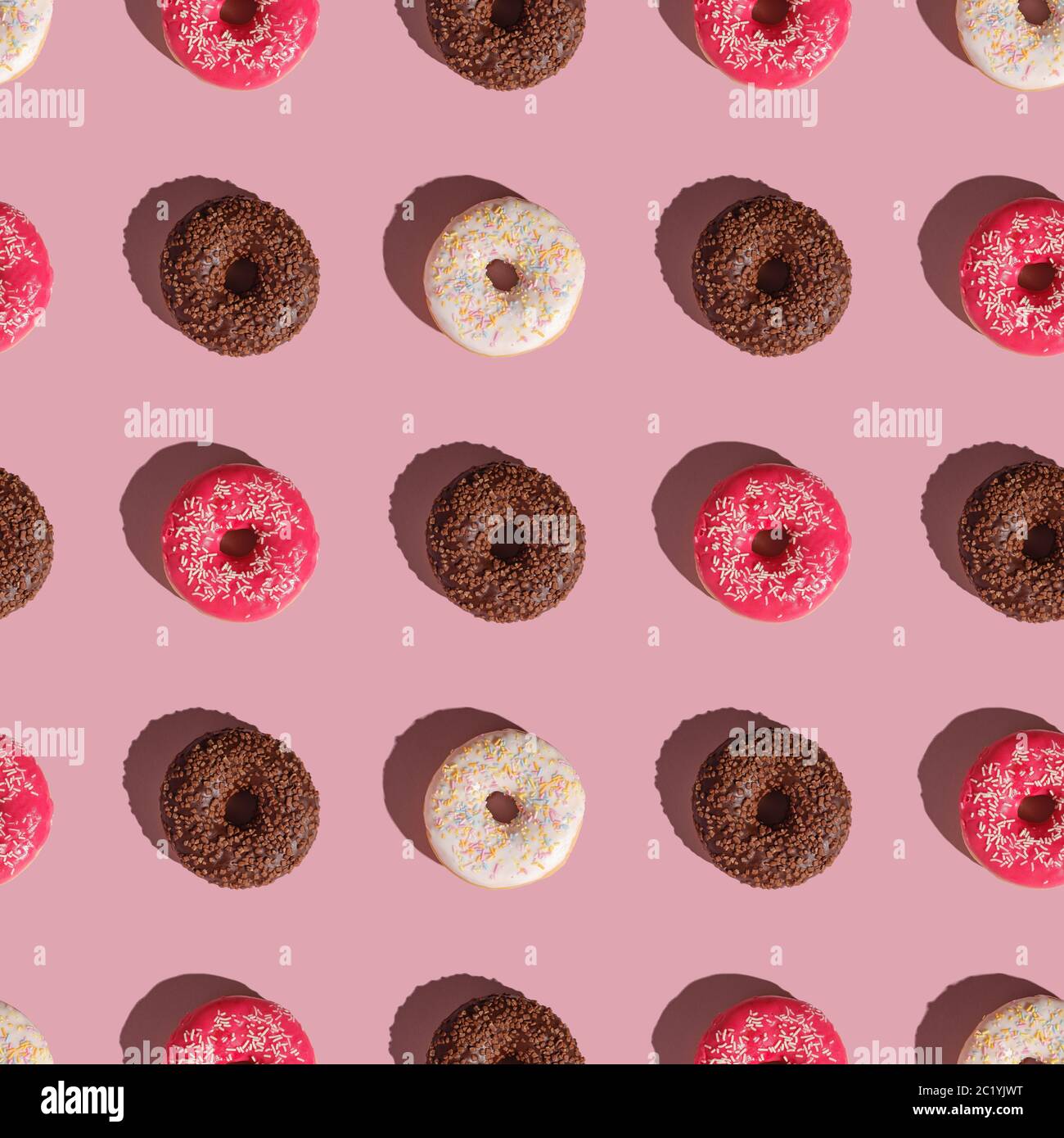 Beignets roses, vanille et chocolat avec saupoudrer, motif sans couture, dessert glacé sucré sur fond rose minimal, vue du dessus Banque D'Images