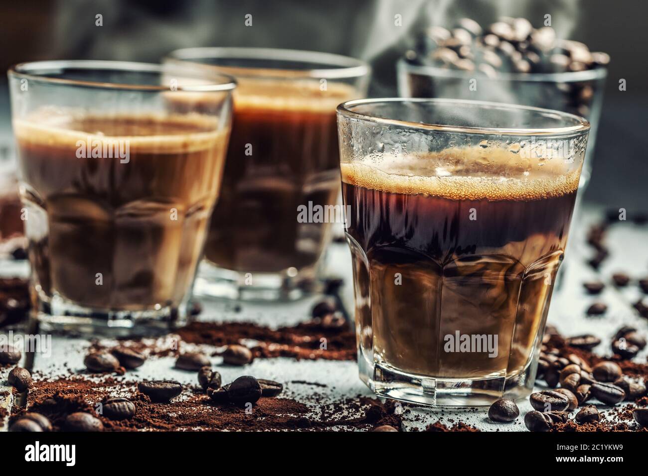 Café dans des tasses en verre mélangé à la crème et aux grains de café saupoudrées Banque D'Images