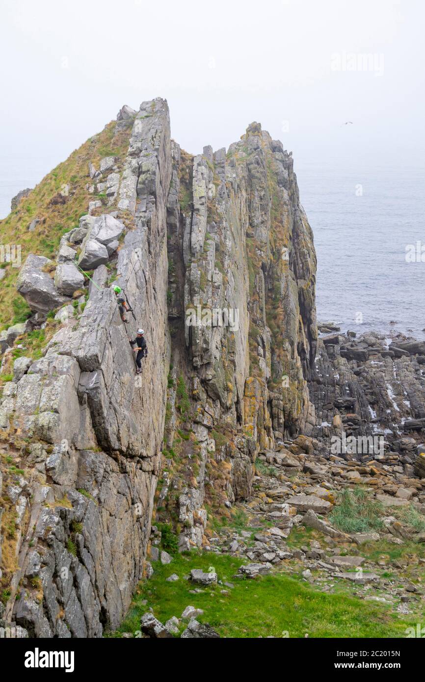 CULLEN TOWN MORAY COAST SCOTLAND DEUX GRIMPEURS INTRÉPIDES SUR UN FRONT DE ROCHE UTILISÉ POUR LA PRATIQUE PAR LES GRIMPEURS DE ROCHE Banque D'Images
