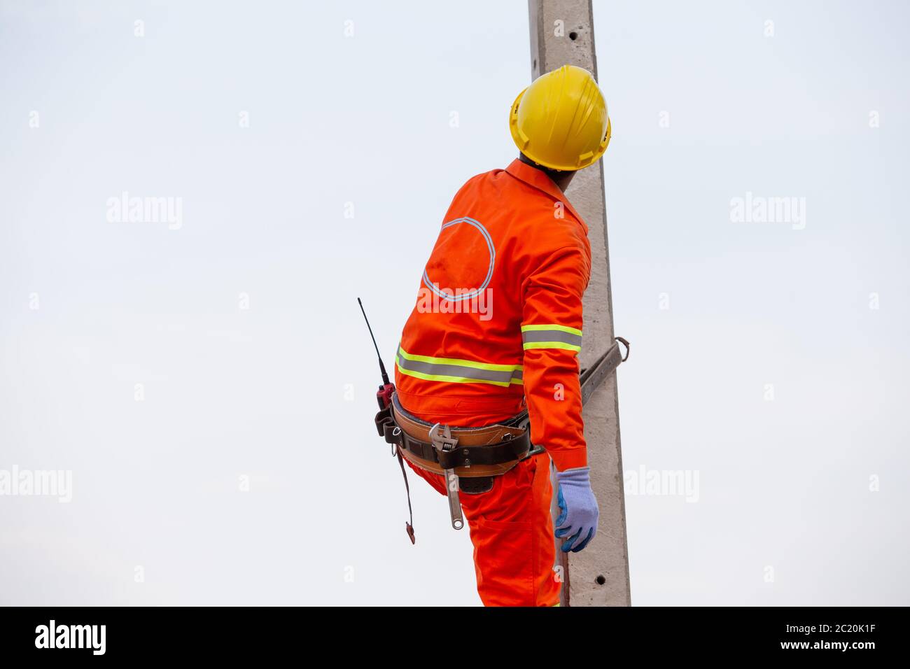 Électriciens en uniforme travaillant sur des poteaux électriques haute tension avec des équipements de sécurité. Banque D'Images