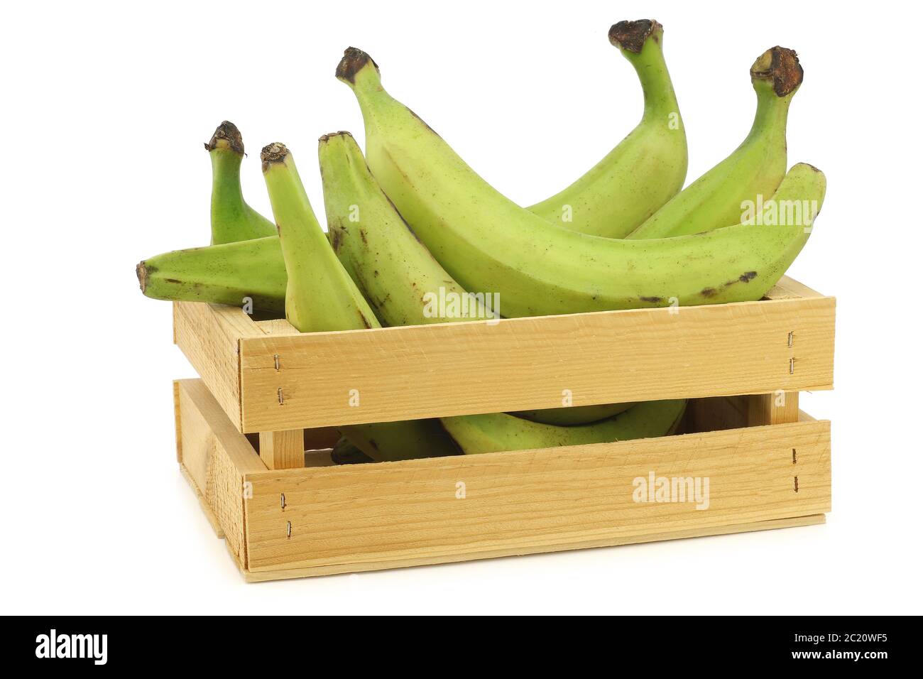 bananes non mûres (bananes plantain) dans une caisse en bois sur fond blanc Banque D'Images