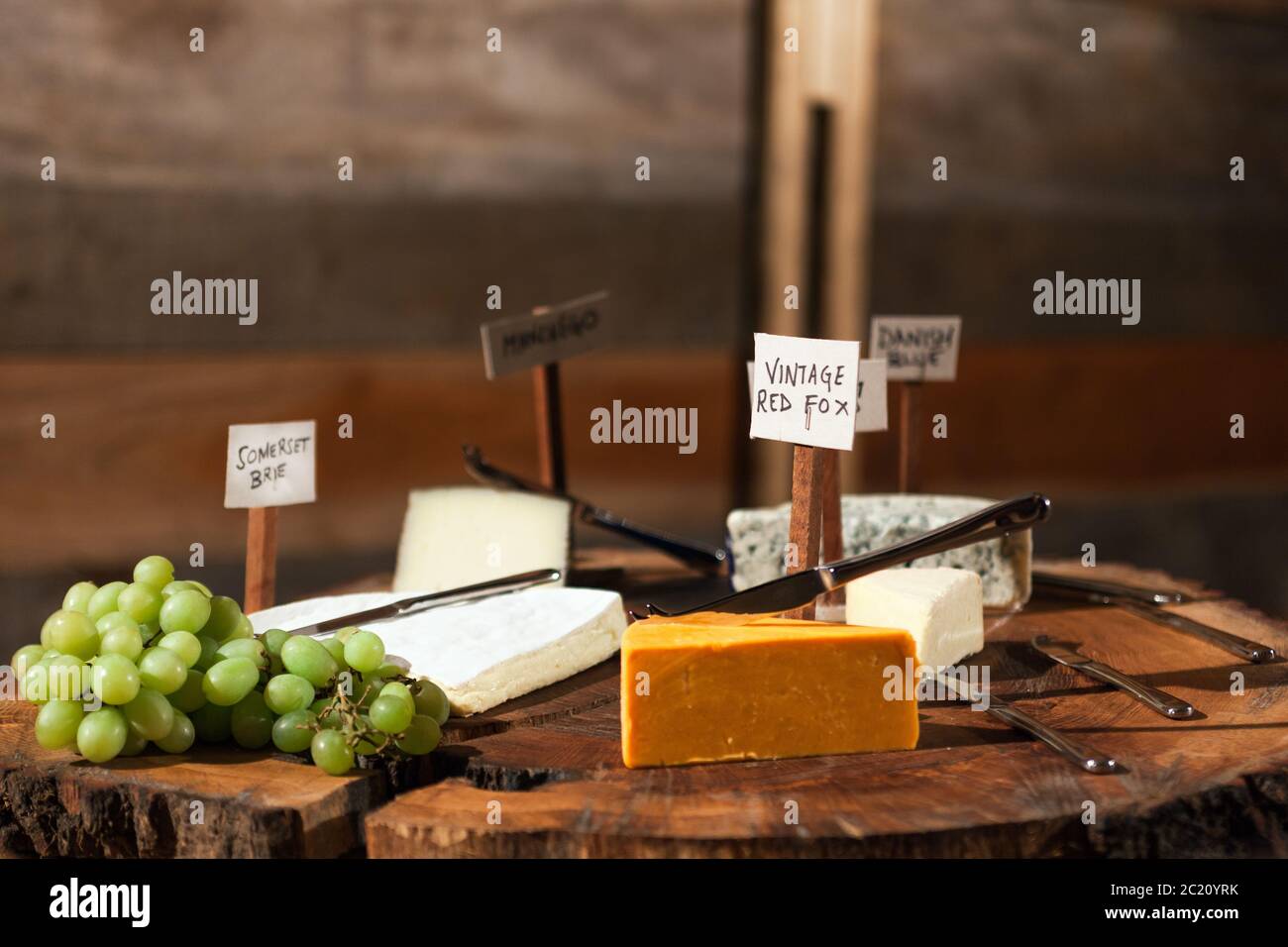 Plateau de fromages rustique avec une sélection de fromages étiquetés et de viandes séchées au raisin. Banque D'Images