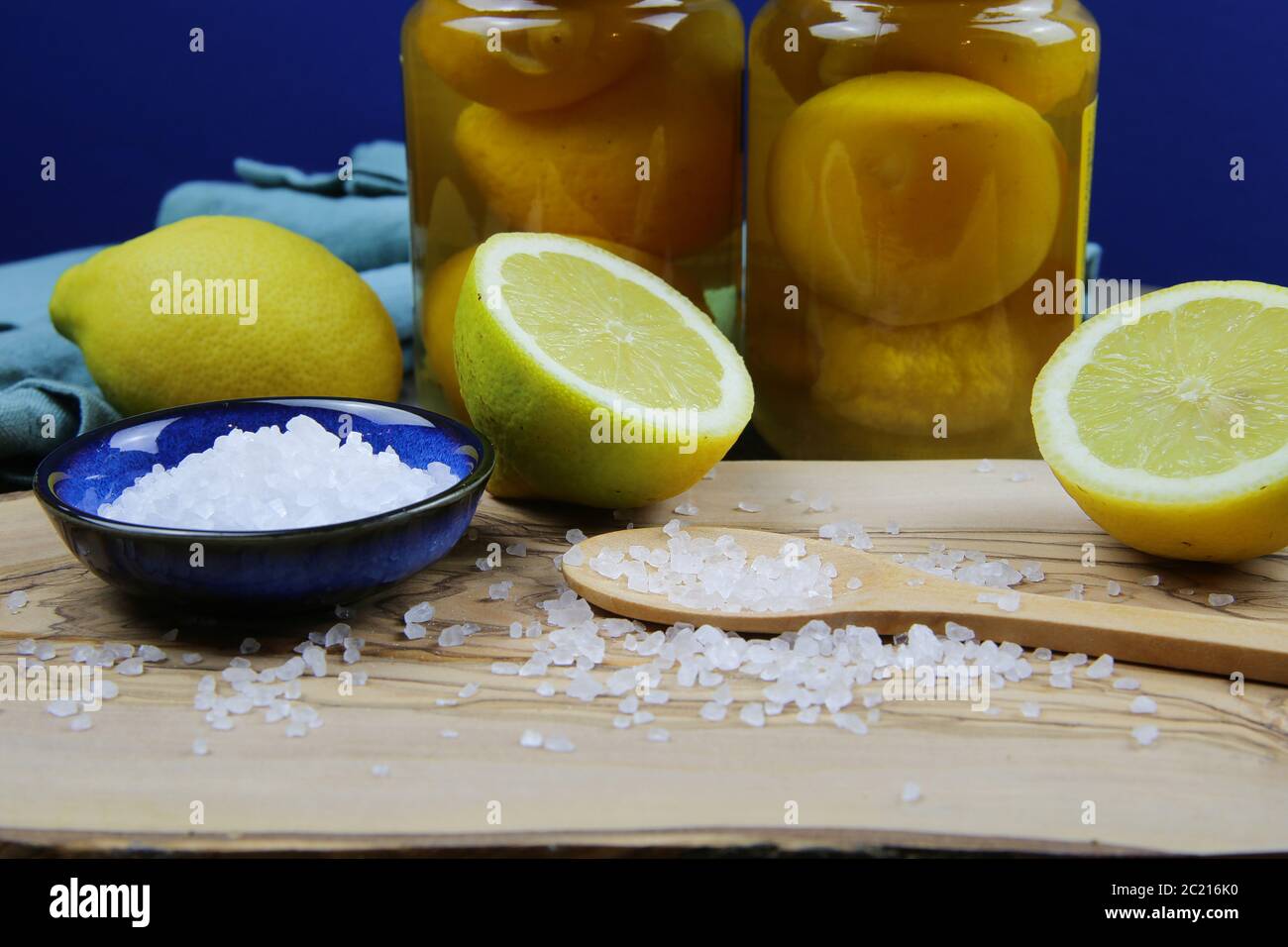 Préparation de citrons salés marinés conservés au maroc : gros plan de tranches isolées d'agrumes jaunes, bol bleu et cuillère en bois avec sa mer épaisse Banque D'Images