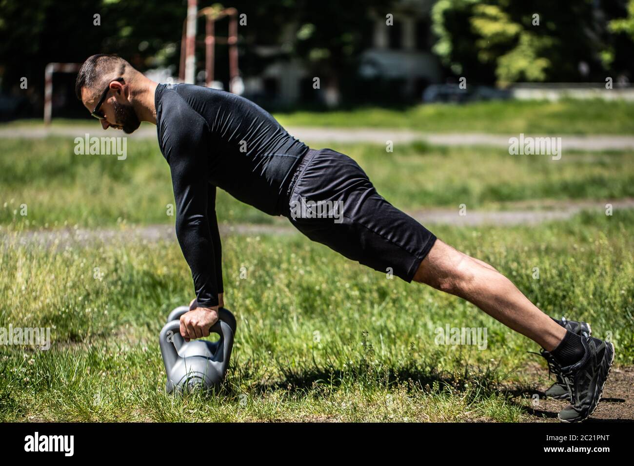 Exercice en plein air. Un athlète masculin s'entraînant avec kettlebell dans le parc. Banque D'Images