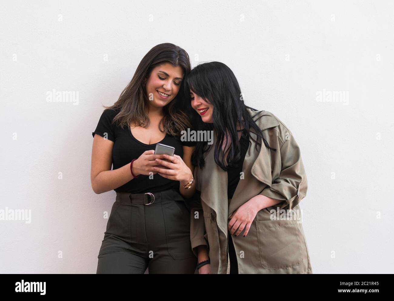Deux jeunes femmes utilisent un smartphone sur un blanc arrière-plan Banque D'Images