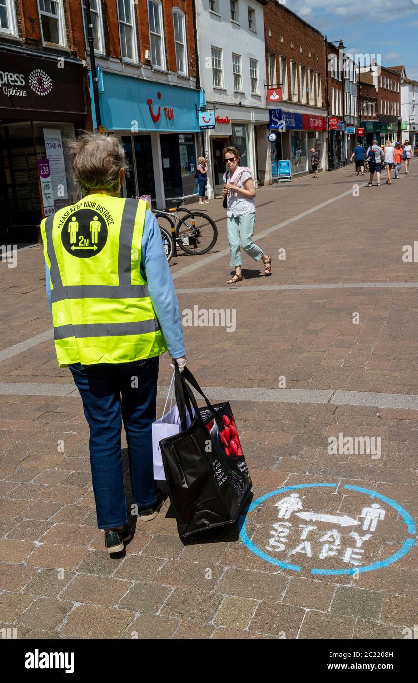 Newbury, Berkshire, Angleterre, Royaume-Uni. Juin 2020. Une cabas âgée portant une veste réfléchissante vous dit : gardez une distance de 2 M. Sur High Street Banque D'Images