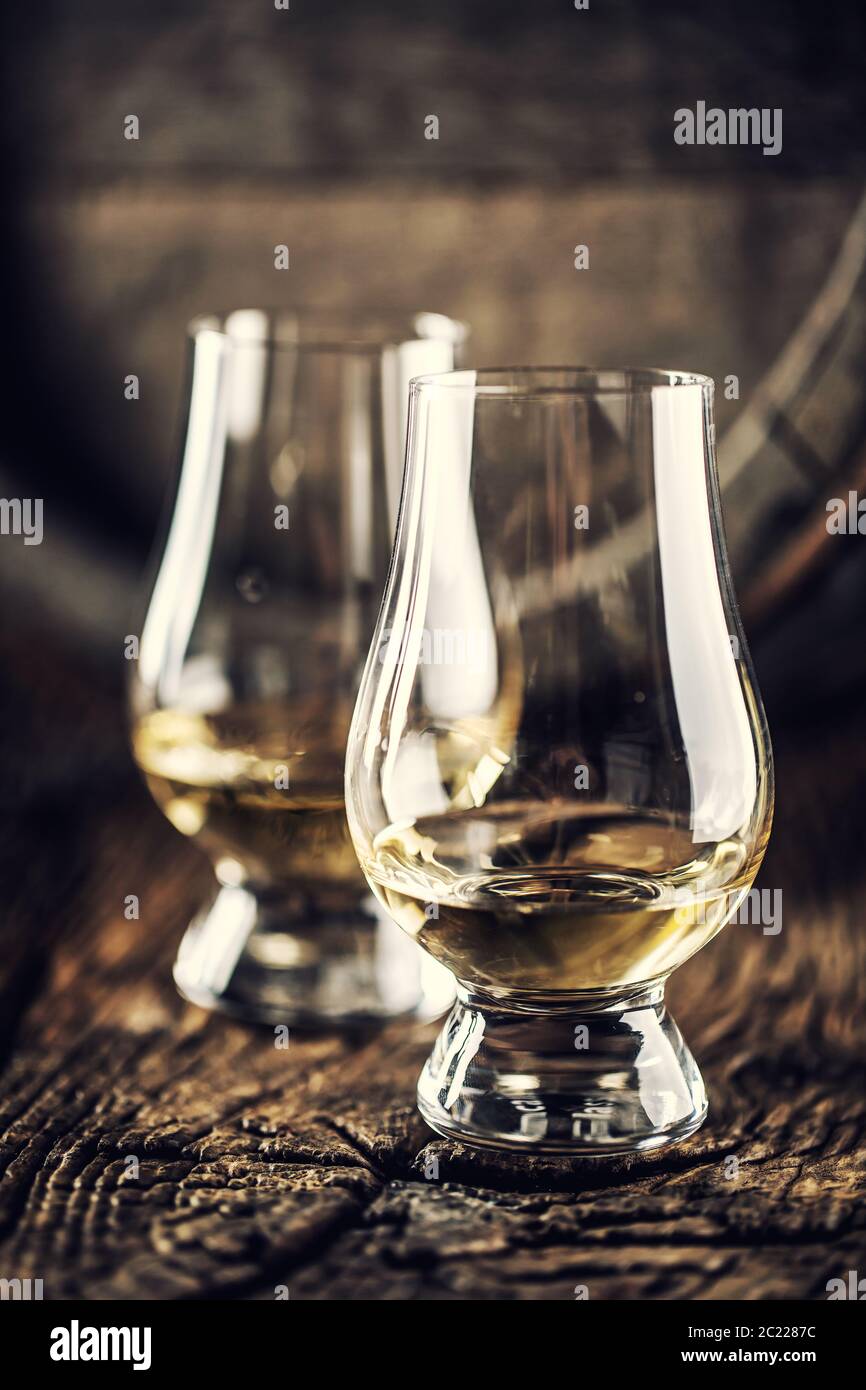 Deux verres de dégustation de whisky Glencairn sur bois vintage et fût en bois sombre à l'arrière Banque D'Images