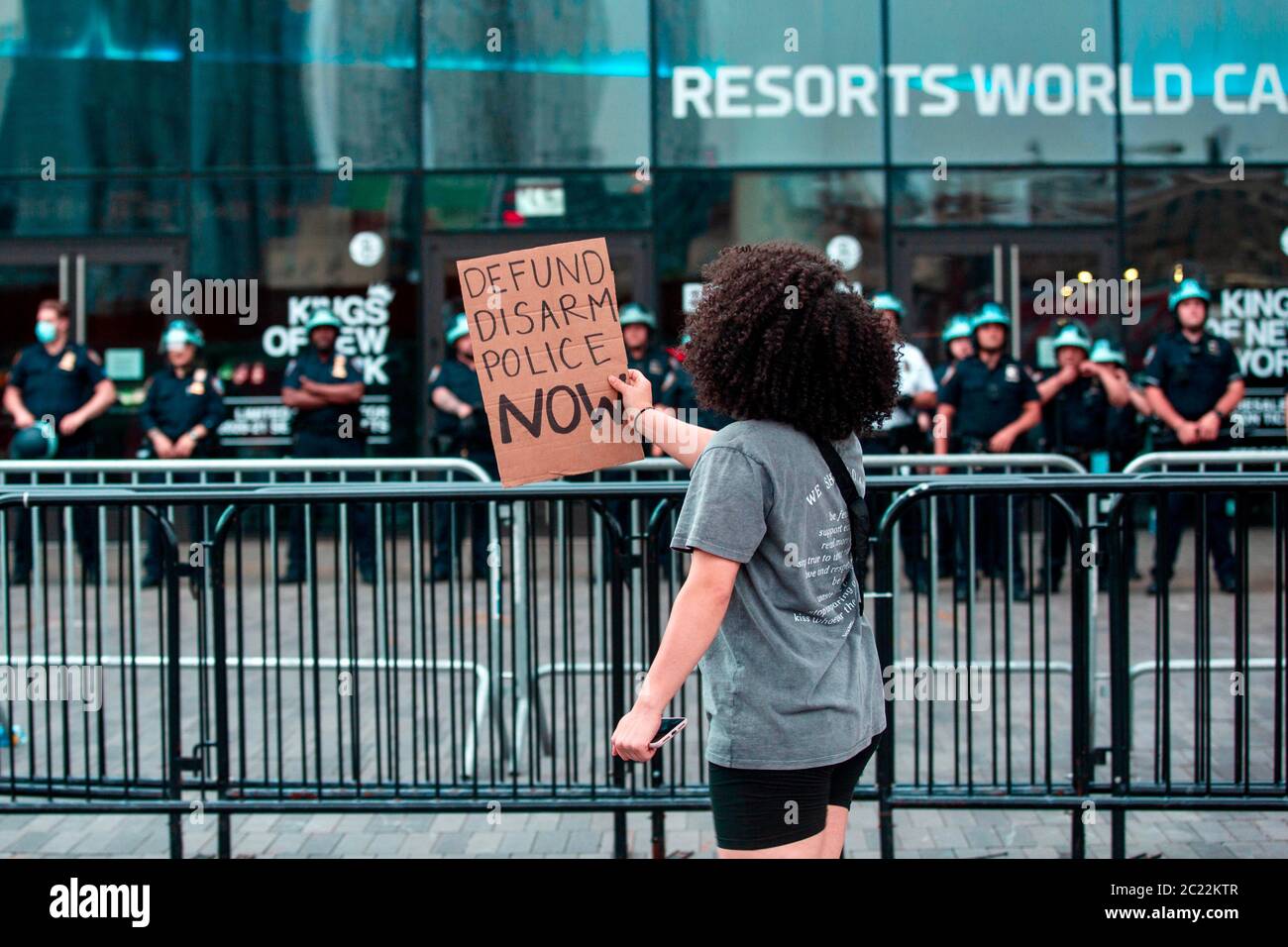 Barclays Center, Brooklyn, le 4 juin 2020. Une jeune femme se tient devant une foule d'agents de police armés qui élèvent une pancarte et crient sa fonctionnaire Banque D'Images
