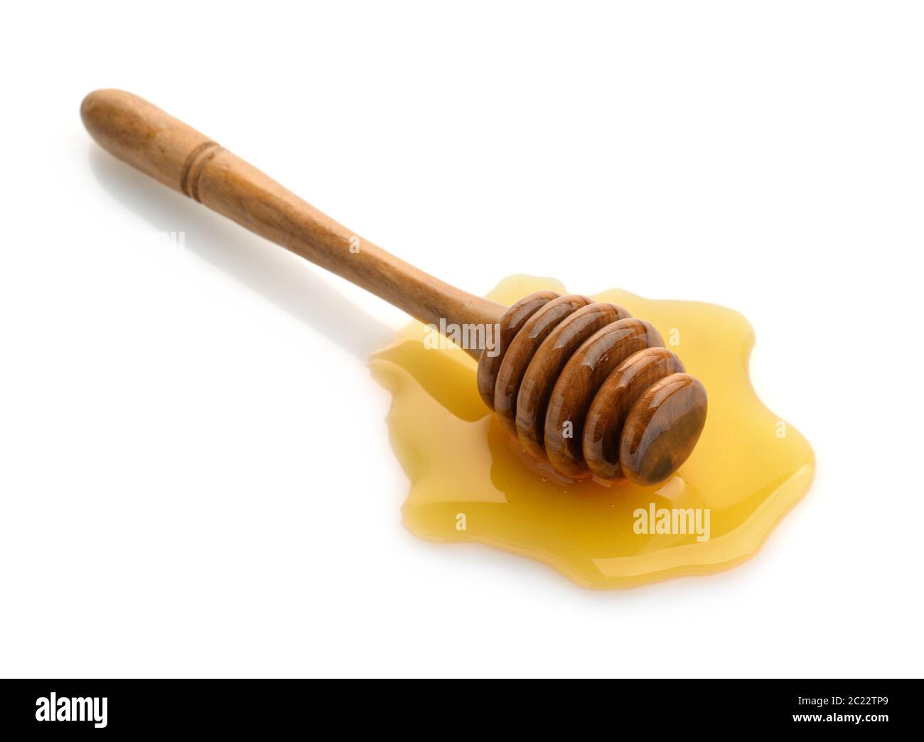 Un balancier en bois de miel dans une flaque de miel isolée sur blanc Banque D'Images