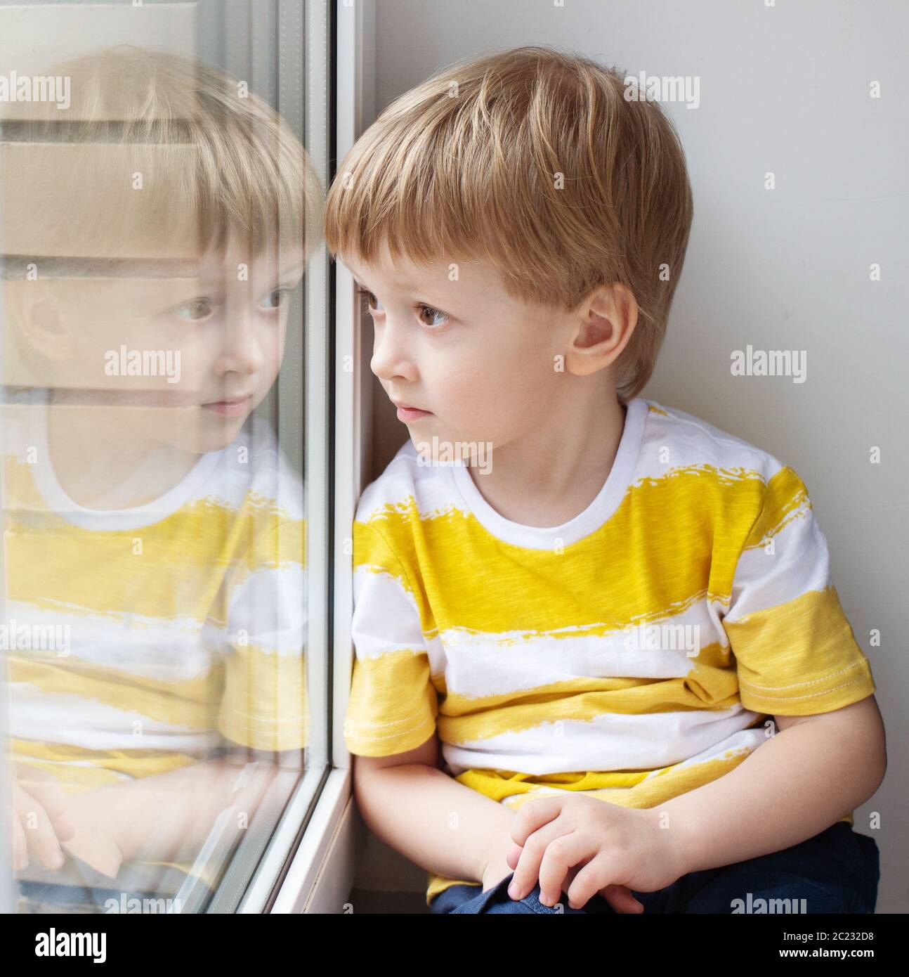 Triste enfant assis sur la fenêtre. Concept - auto-isolement Banque D'Images