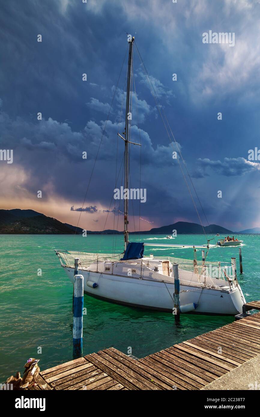 Le yacht amarré sur le lac Iseo également connu sous le nom de Sebino dans le temps pré-tempête sous la lumière du soleil du soir. Lombardie, Italie. Banque D'Images