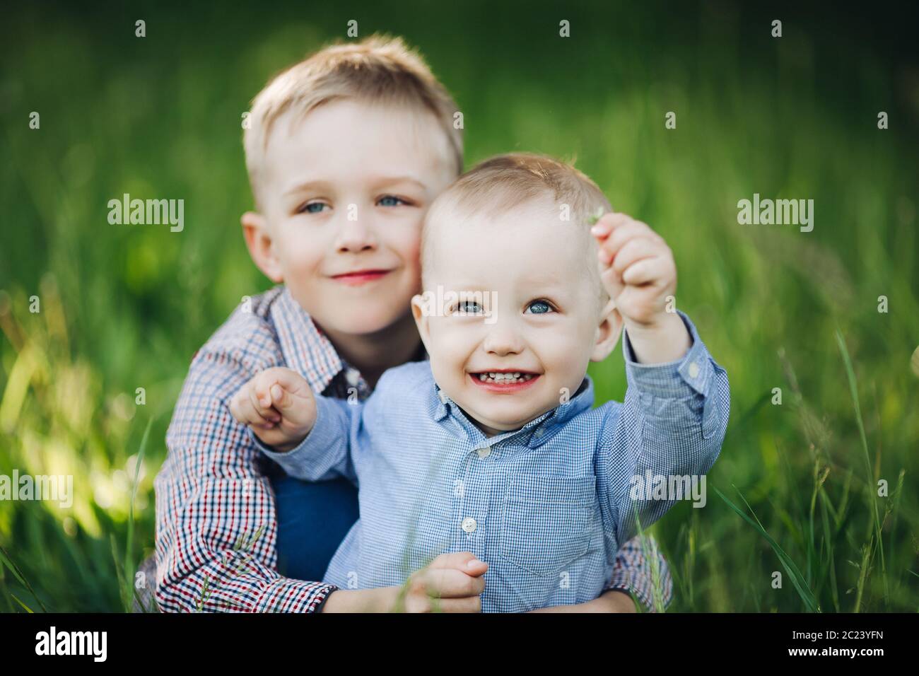 Deux petit frère embrassant et en regardant la caméra en parc. Banque D'Images