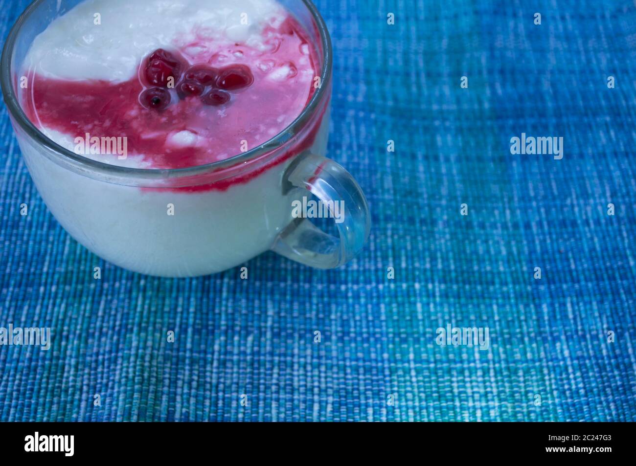 Yaourt dans une tasse transparente avec des baies de cassis et du sirop de sucre. Photo avec place pour le texte. Produits diététiques, produits laitiers Banque D'Images