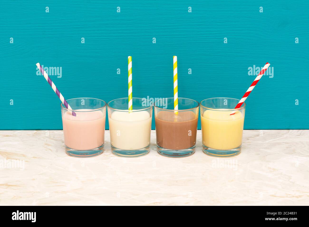 Milkshakes à saveur de fraise -, de chocolat et de banane - lait crémeux et frais avec des pailles en papier rétro verres en verre avec un fond bleu sarcelle Banque D'Images