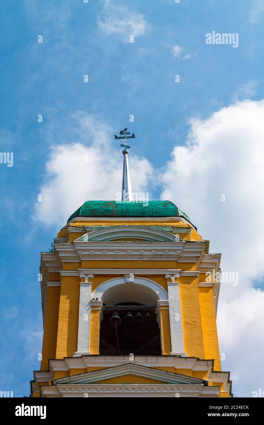 Église chrétienne orthodoxe jaune avec un dôme vert contre un ciel bleu avec des nuages blancs. Banque D'Images