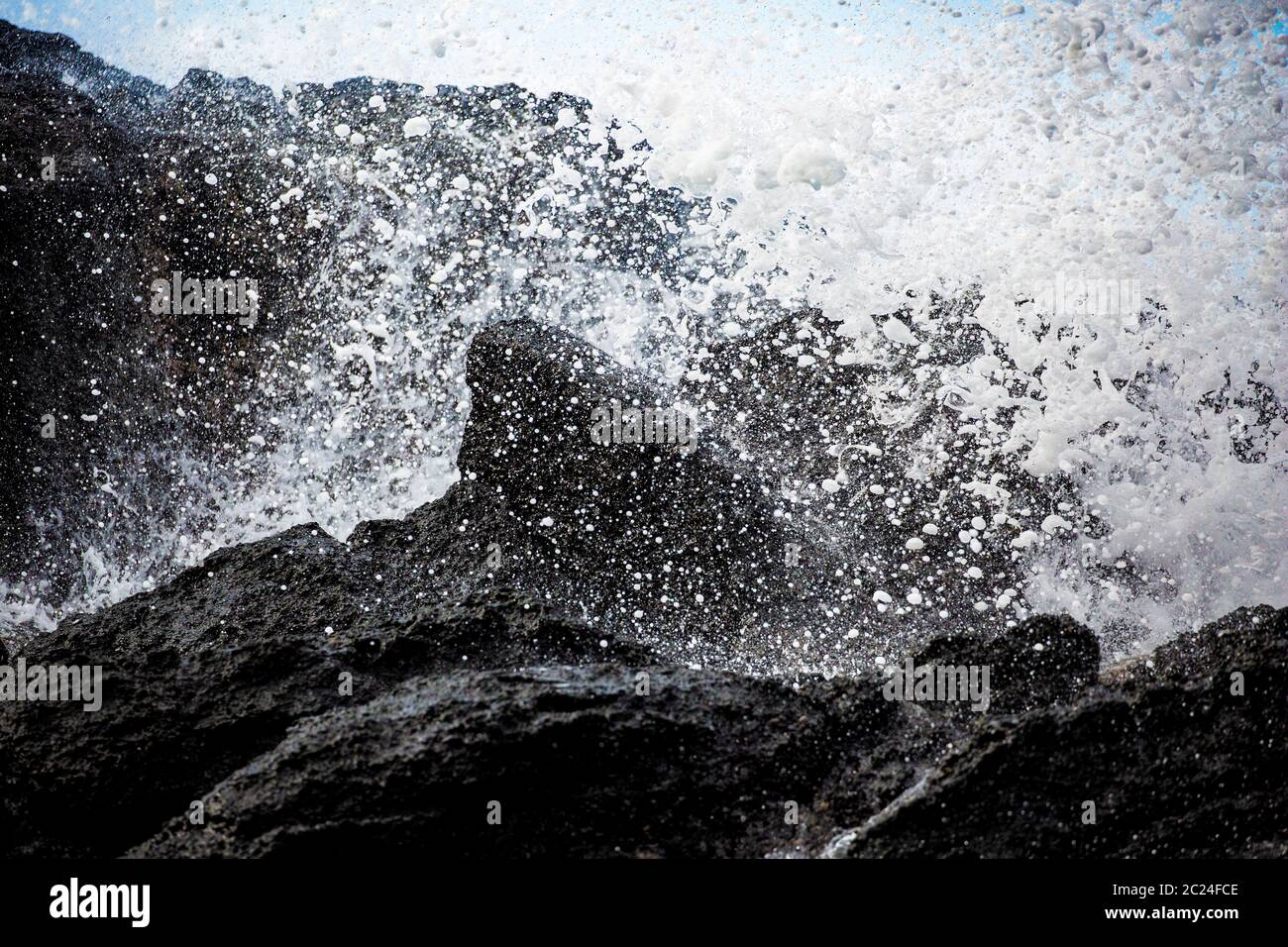 Des gouttes d'eau éclaboutent artistiquement sur des roches volcaniques noires Banque D'Images