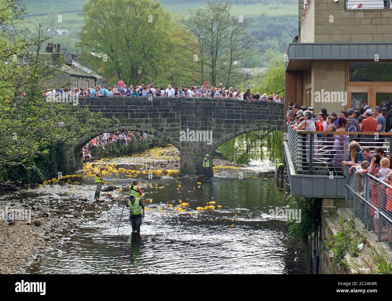 des gens et des bénévoles qui regardent la course annuelle de canard de charité du lundi de pâques au pont hebden Banque D'Images