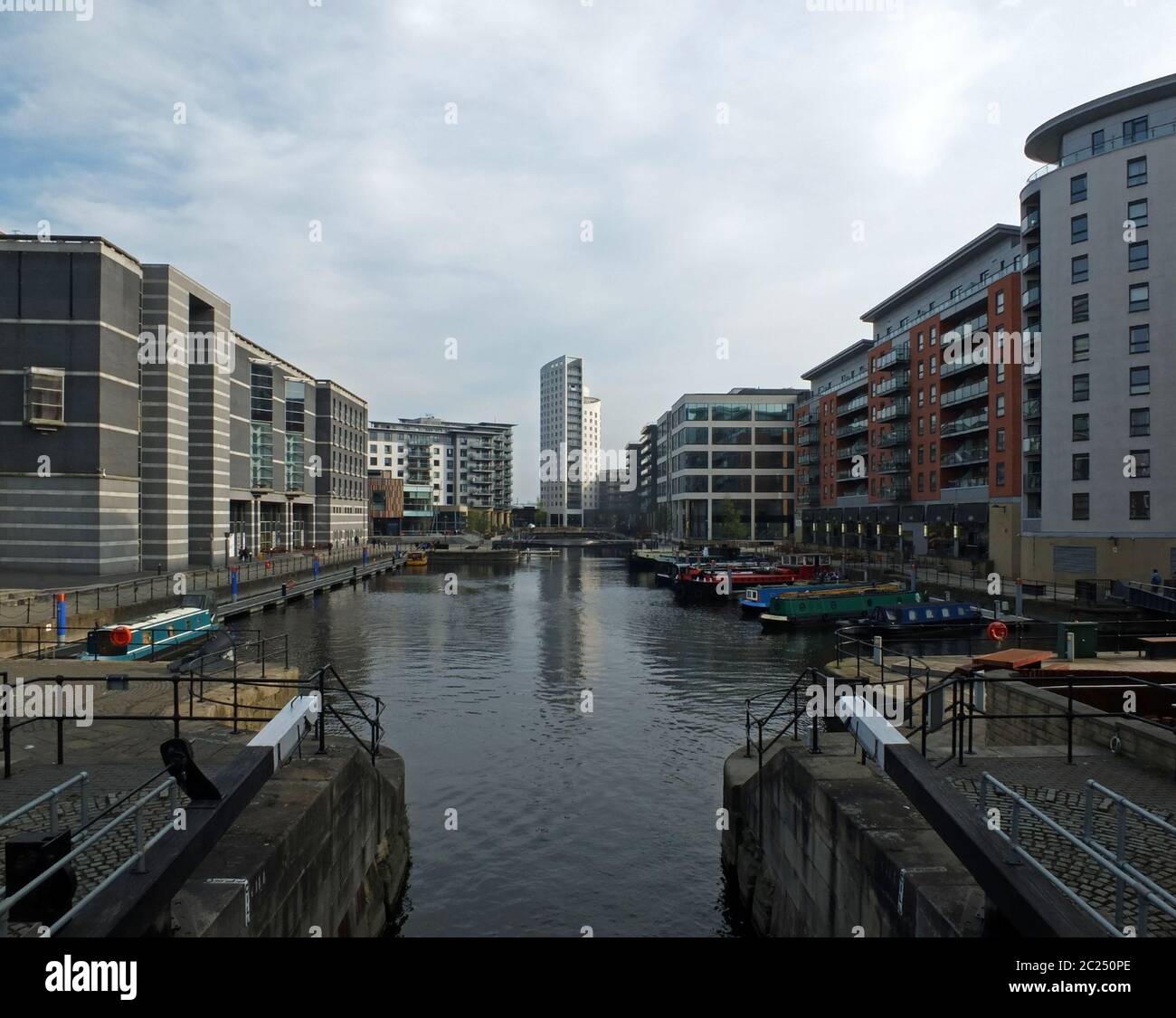 une vue sur le quai de leeds depuis les portes d'écluse montrant des bâtiments de développement au bord de l'eau et des immeubles d'appartements avec des bateaux à moteur amarrés moi Banque D'Images