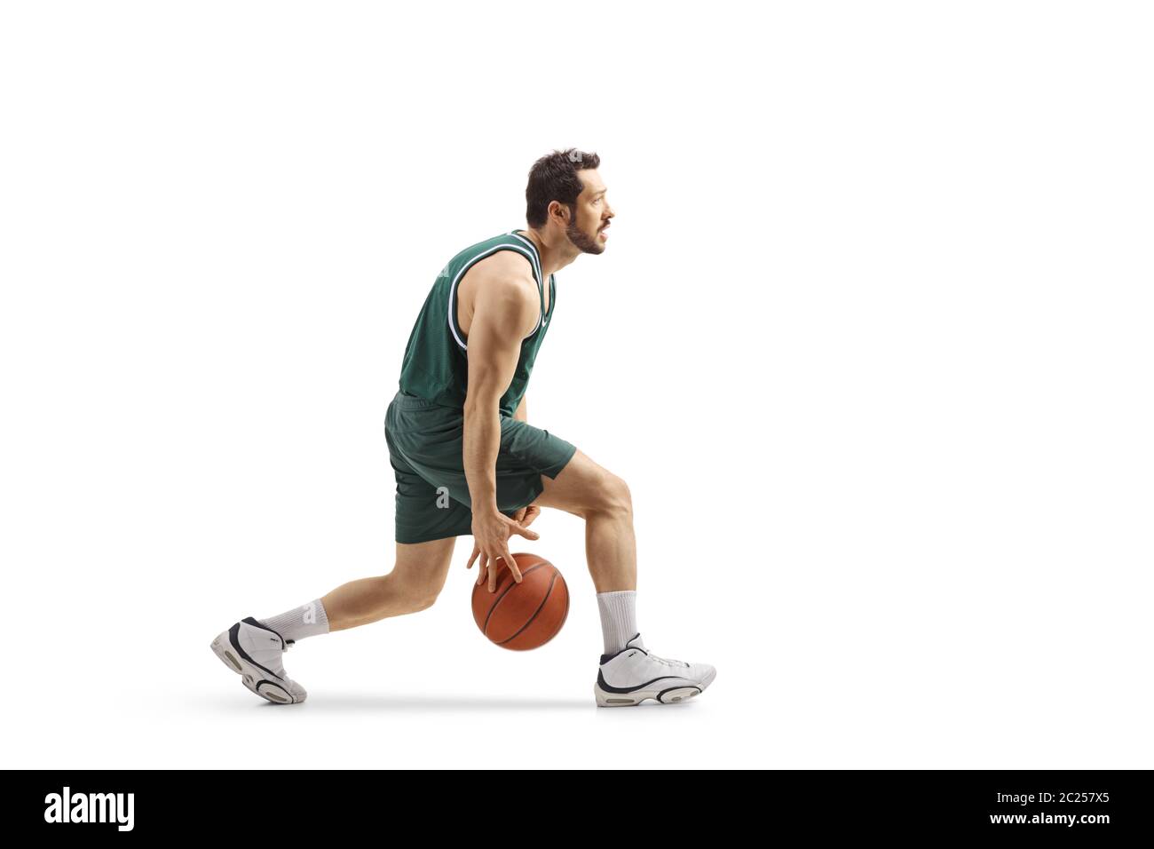 Photo de profil d'un joueur de basket-ball professionnel qui mène une balle entre ses jambes isolée sur fond blanc Banque D'Images
