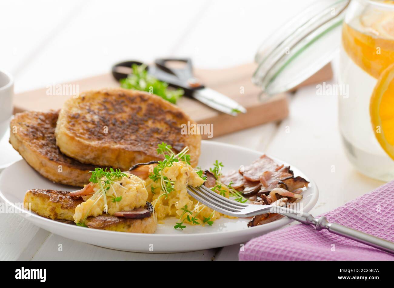 Oeufs brouillés avec du pain doré garni de cresson frais microgreens, eau d'orange Banque D'Images