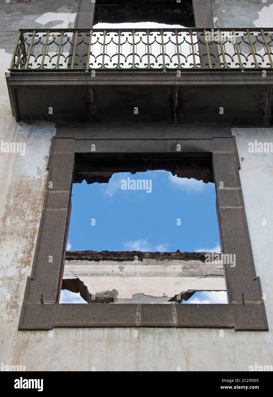 des cadres de fenêtres vides dans une maison abandonnée sans toit avec balcon et murs intérieurs blancs contre un ciel bleu Banque D'Images