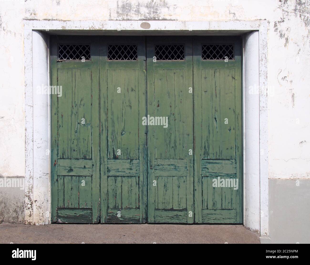 quatre vieilles portes extérieures lambrissés avec peinture craquelée verte décolorée dans un cadre blanc et un mur blanc vieilli Banque D'Images
