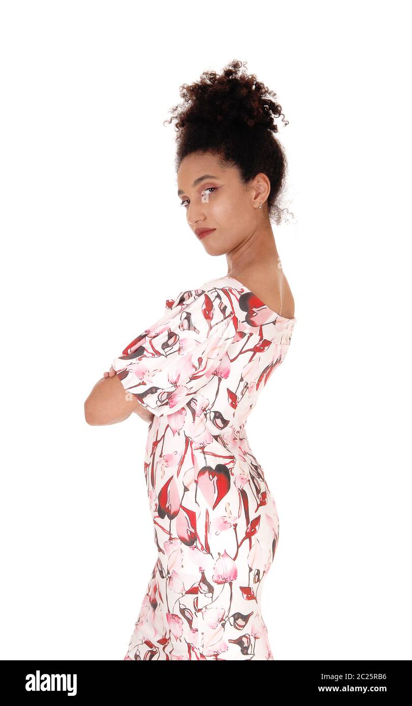 Une magnifique jeune femme multi-raciale debout dans une robe d'été de profil, avec les bras croisés, avec ses cheveux noirs frisés en chignon, isolée pour whi Banque D'Images