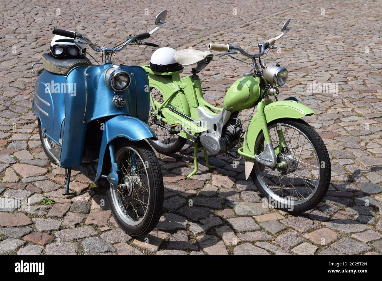 Deux vieilles motos historiques en vert et bleu sur une chaussée pavée Banque D'Images