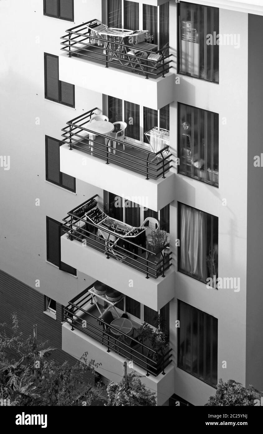 image monochrome d'une rangée de balcons avec tables et chaises dans un immeuble en béton Banque D'Images