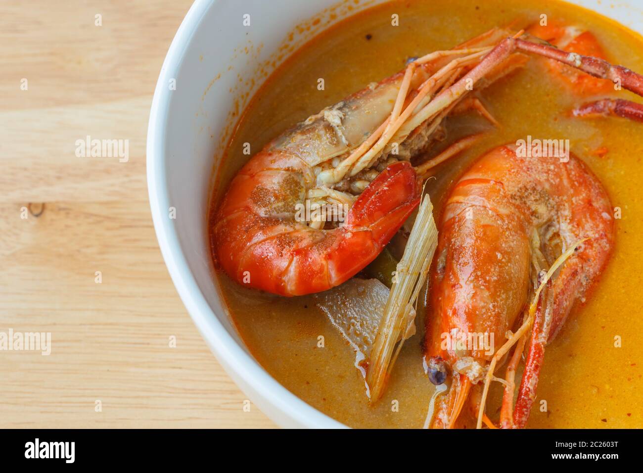 Thai soupe épicée aux crevettes, bol de soupe Tom Yum Thaï épicé sur fond de bois Banque D'Images