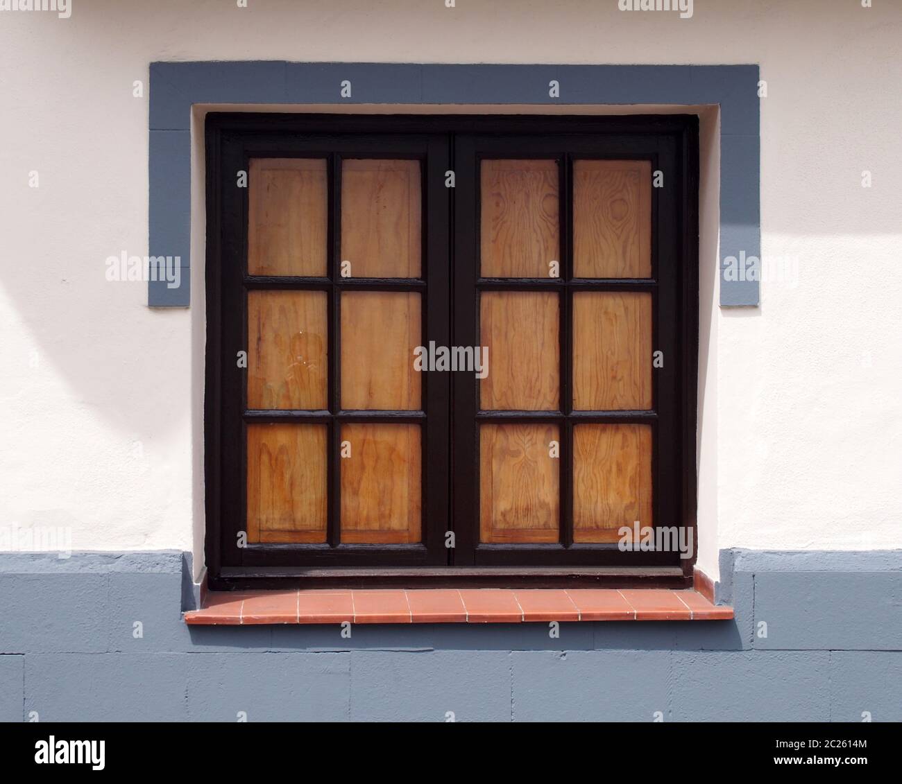 ancienne fenêtre traditionnelle en bois avec des panneaux de verre fermé volets internes sur un mur blanc propre maison avec un cadre gris peint a Banque D'Images