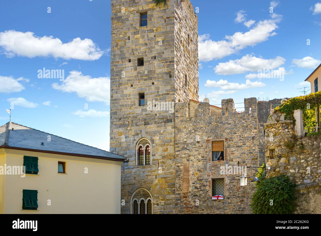 Une italienne s'incline de sa fenêtre d'appartement dans une tour médiévale le long des anciens murs de la ville de Portovenere, en Italie Banque D'Images
