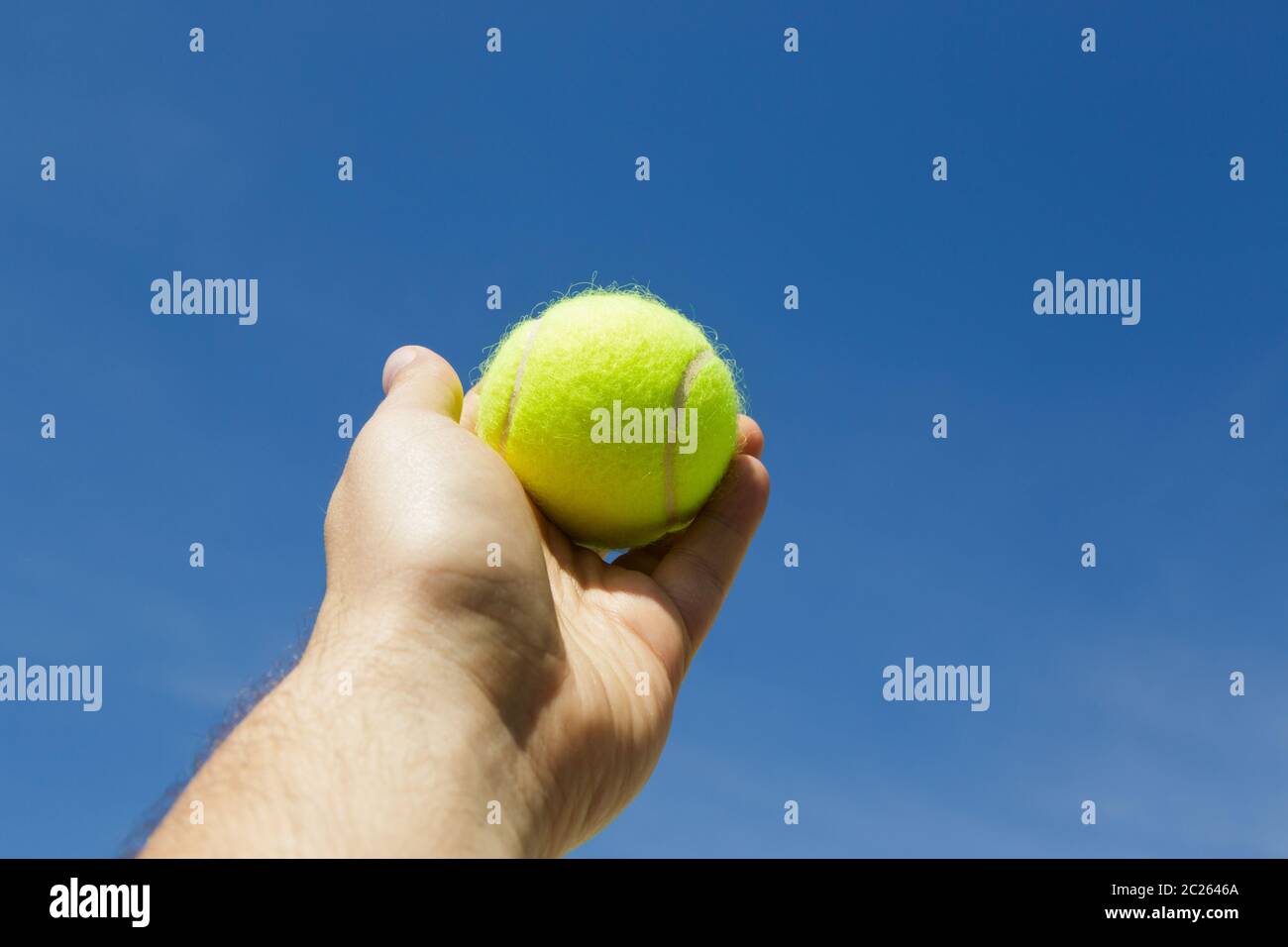 Homme tenant et servant un tennisball jaune contre le ciel bleu. Sports Banque D'Images