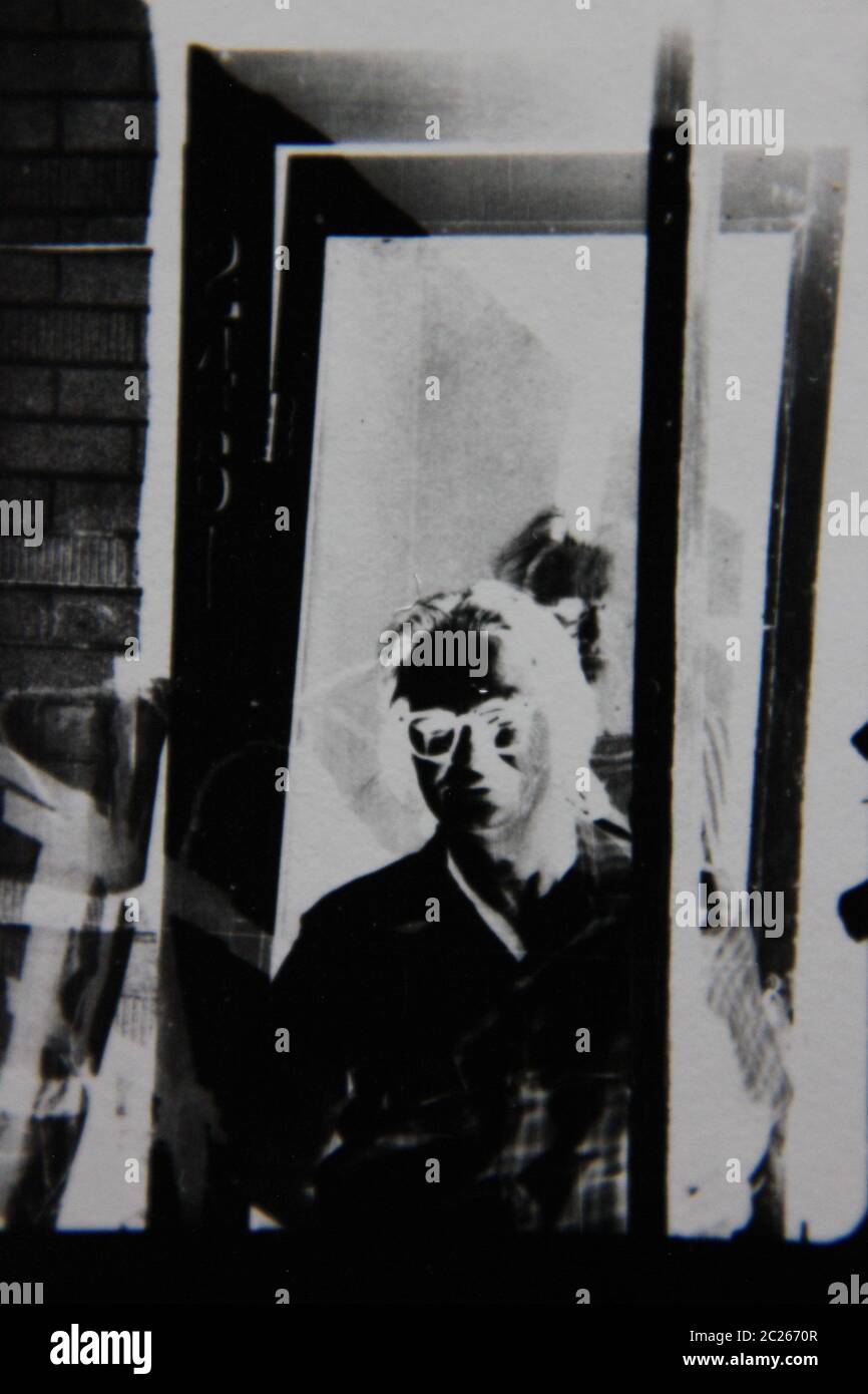 Fin années 70 vintage noir et blanc extrême photographie de peeping tom peeking autour du coin. Banque D'Images