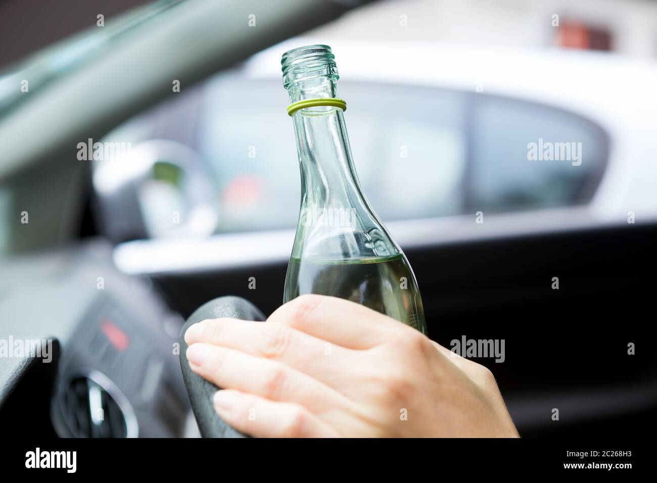 Jeune conducteur ivre buvant une bouteille de vin pendant la conduite de la voiture. Banque D'Images