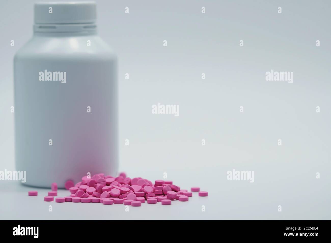 Comprimés roses avec flacon fermé d'étiquette vierge sur fond blanc avec espace de copie. Pilule de warfarine. Médicament anticoagulant. Pharmacie pharmacie Banque D'Images