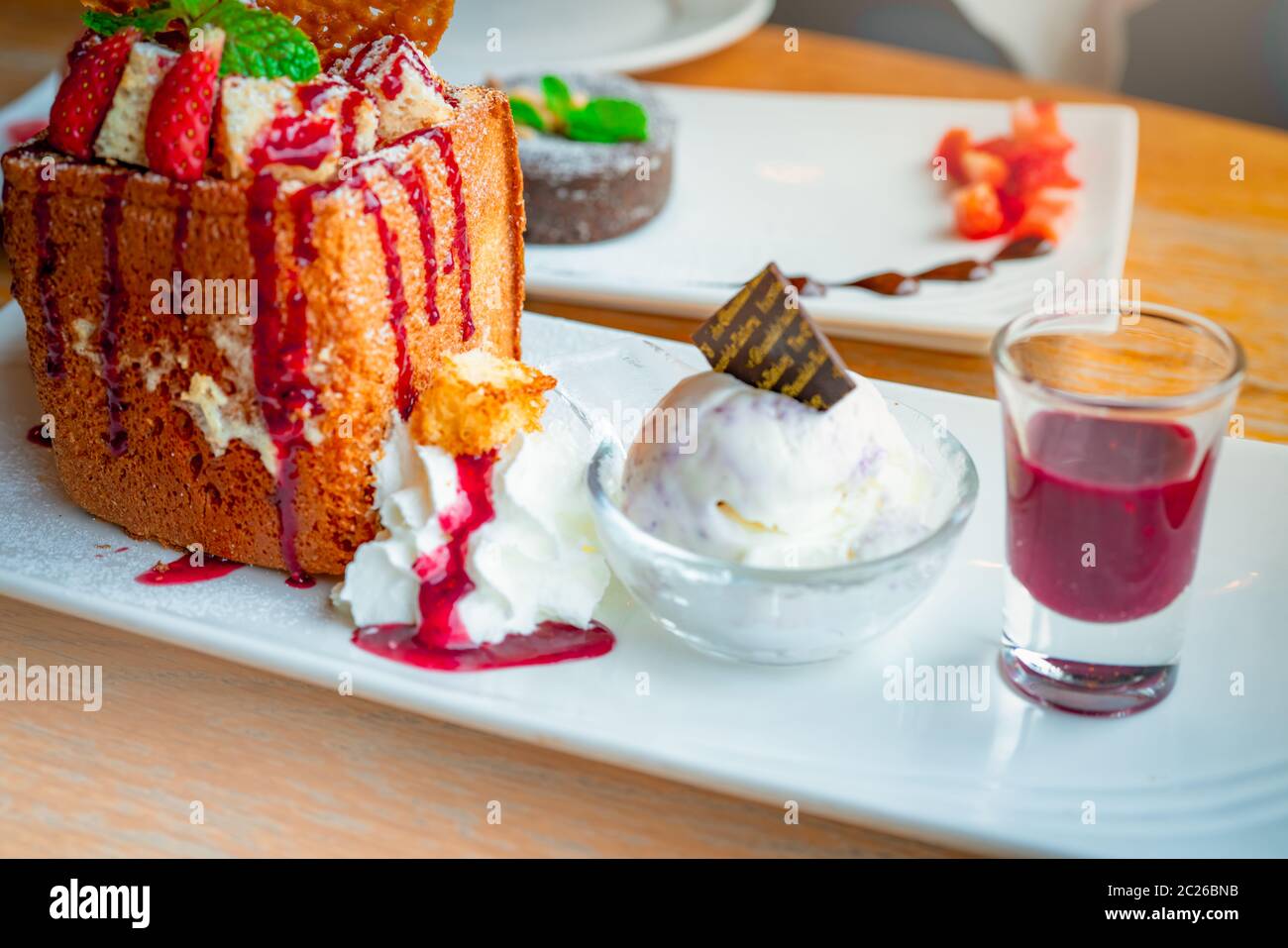 Toast au miel avec garniture fraises, un côté de la crème fouettée, crème glacée à la vanille. Toast de pain sur un plat blanc sur fond flou de lave de chocolat c Banque D'Images