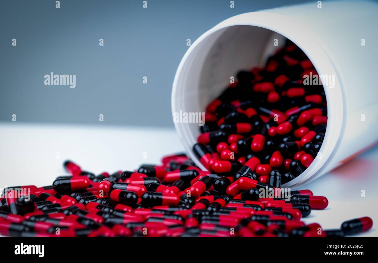 Rouge-noir capsule antibiotique comprimés renverse la bouteille en plastique blanc contenant. L'industrie pharmaceutique. Médicament d'ordonnance. La médecine de la tétracycline. Ant Banque D'Images