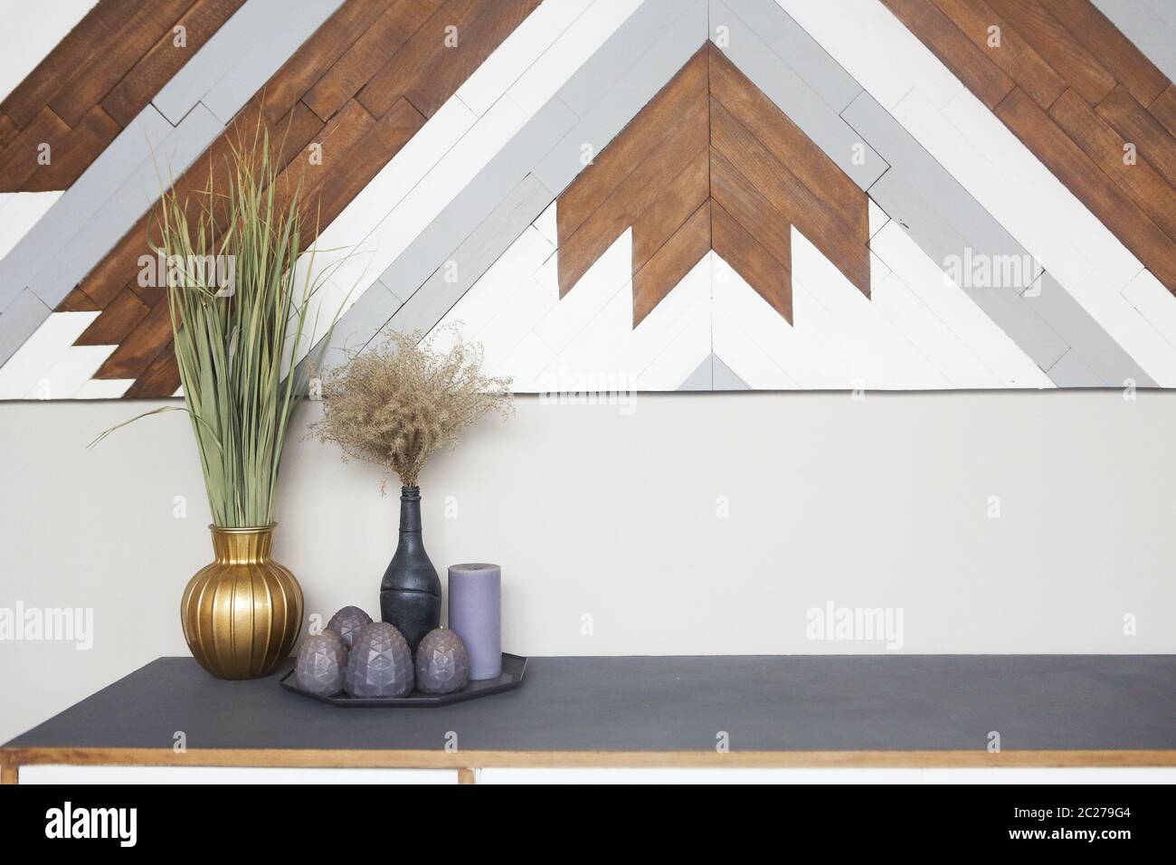 Partie de l'intérieur de la pièce avec commodes en bois, vases vintage et bougies contre les murs clairs Banque D'Images