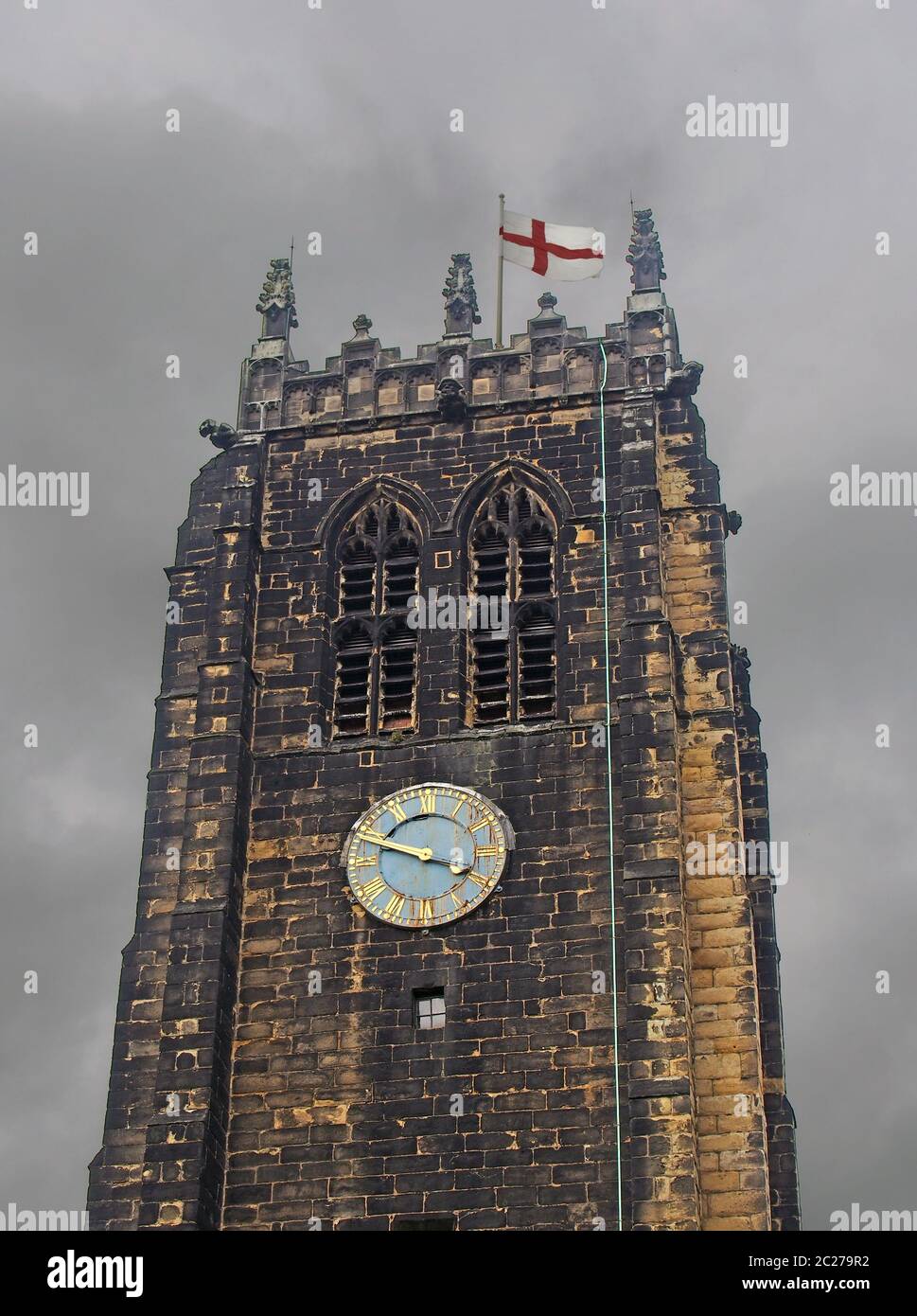 la tour et l'horloge de la cathédrale de halifax dans le west yorkshire contre un ciel gris nuageux avec un drapeau anglais Banque D'Images