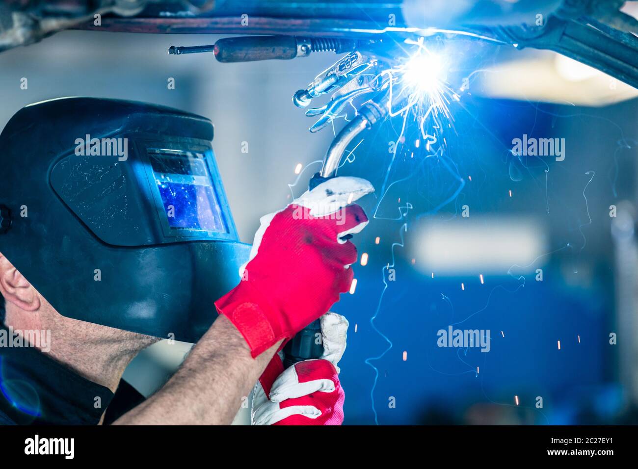 Un travailleur manuel portant un masque de protection soudant du métal dans le service automobile Banque D'Images