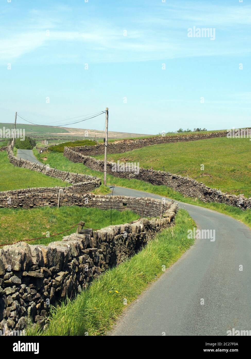 un carrefour sur une ruelle étroite sinueuse de campagne bordée par des murs de pierre sèche dans la campagne vallonnée du yorkshire dales avec bleu été sk Banque D'Images