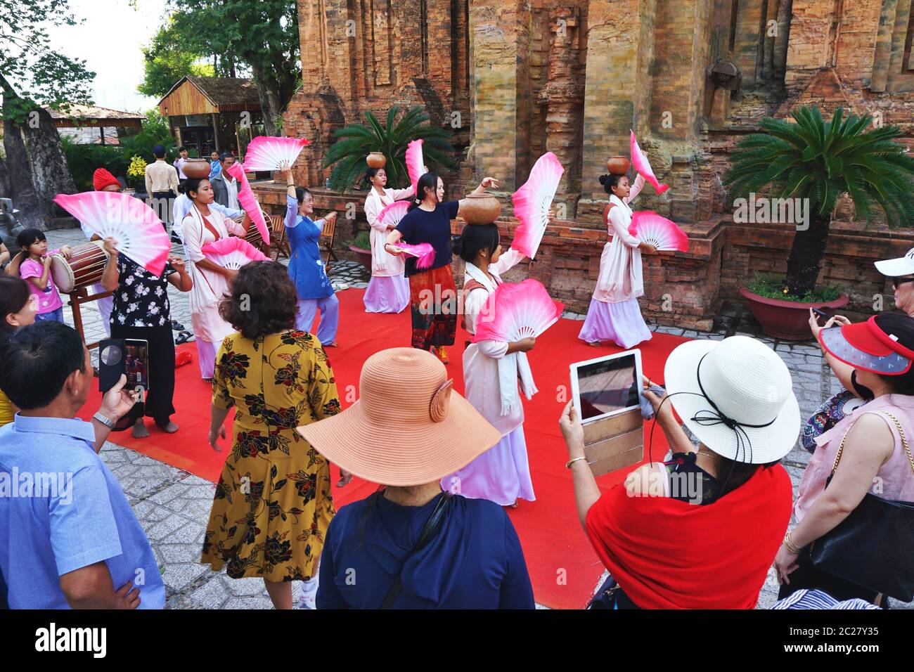 Le 3 juin 2020, de jeunes femmes costumées effectuent une danse ethnique traditionnelle au temple de Cham, à Nha Trang, au Vietnam. Plusieurs touristes se joignent à l'amusement. Banque D'Images
