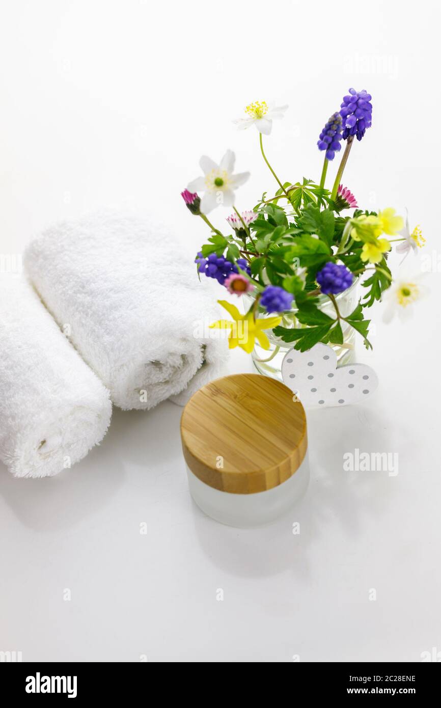 Serviettes à côté d'un pot crème devant un fond blanc et fleurs dans un vase. Banque D'Images